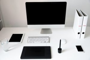 Closeup image of a computer with blank screen and gadgets on the table in office